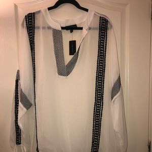 Plus size white flowy top with black stitching.